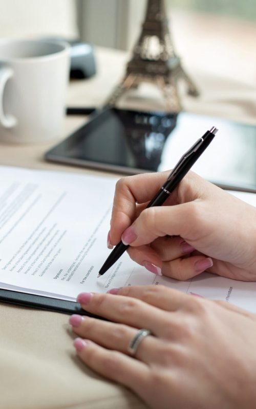 A female travel agent in the office signs a contract, close-up.